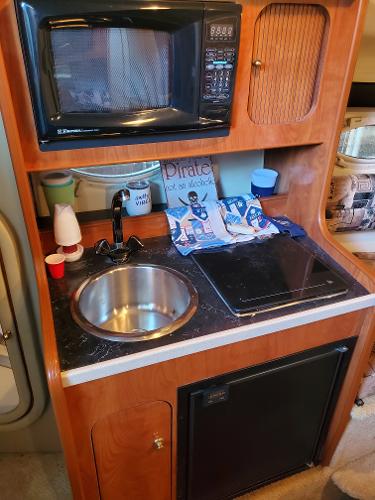 Slide: The Image of 2003 Rinker 270 Fiesta Vee Cr kitchenette with microwave, sink, and stove. - 8