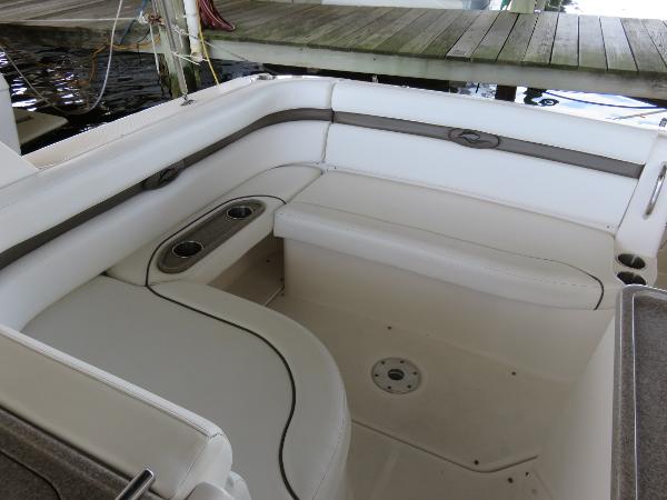 Slide: The Image of 2008 Rinker 280 Express Cruiser interior seating with cup holders, docked by wooden pier. - 19