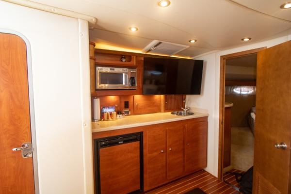 Slide: The Image of 2008 Rinker 400 Express Cruiser interior kitchen with microwave, TV, and wooden cabinets. - 11