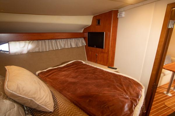 Slide: The Image of 2008 Rinker 400 Express Cruiser cabin with bed, TV, and wooden interior. - 16