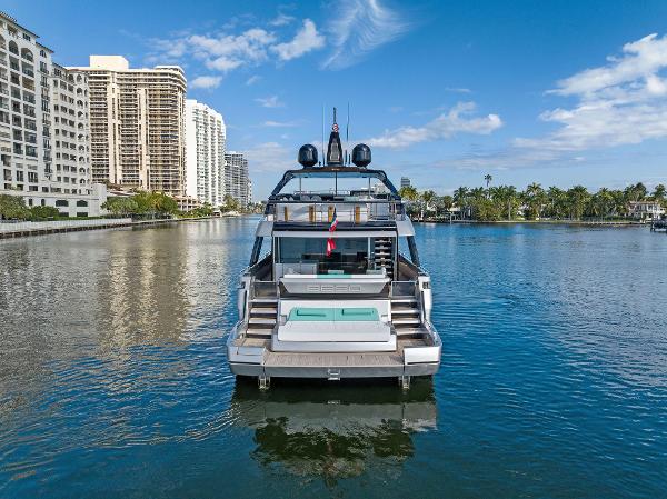 Slide: The Image of 2024 Riva 102 Corsaro Super yacht on a serene waterway with cityscape backdrop. - 10