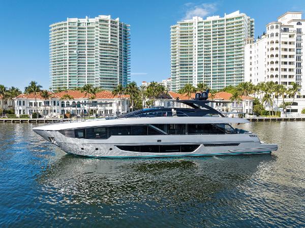 Slide: The Image of 2024 Riva 102 Corsaro Super yacht cruising near luxury waterfront buildings. - 2