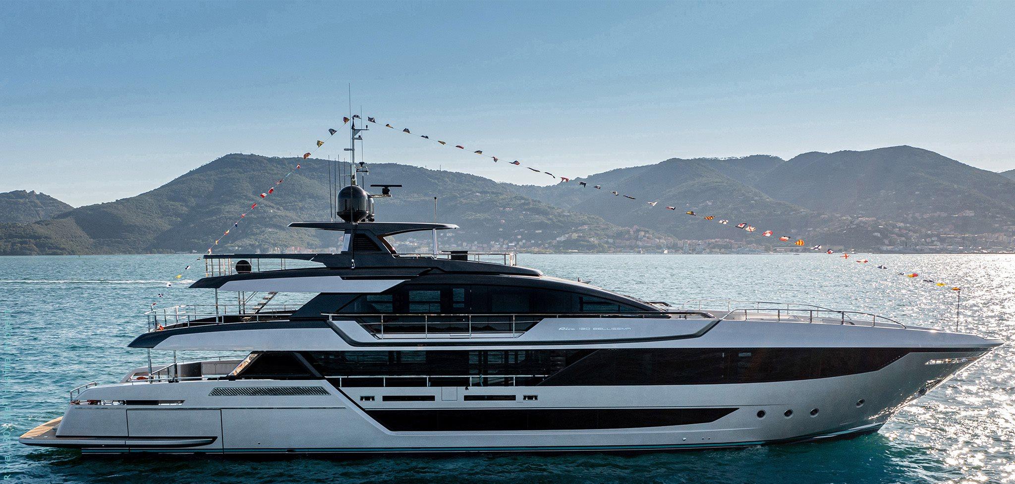 Slide: The Image of 2023 Riva 130' BELLISSIMA luxury yacht on the water with scenic mountain backdrop. - 0