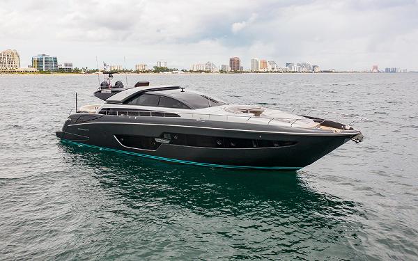 Slide: The Image of 2017 Riva 88 Domino Super yacht cruising near a coastal city skyline. - 1