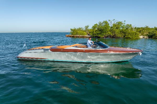Slide: The Image of 2020 Riva Aquariva Super luxury boat cruising on clear blue water near a lush green island. - 2