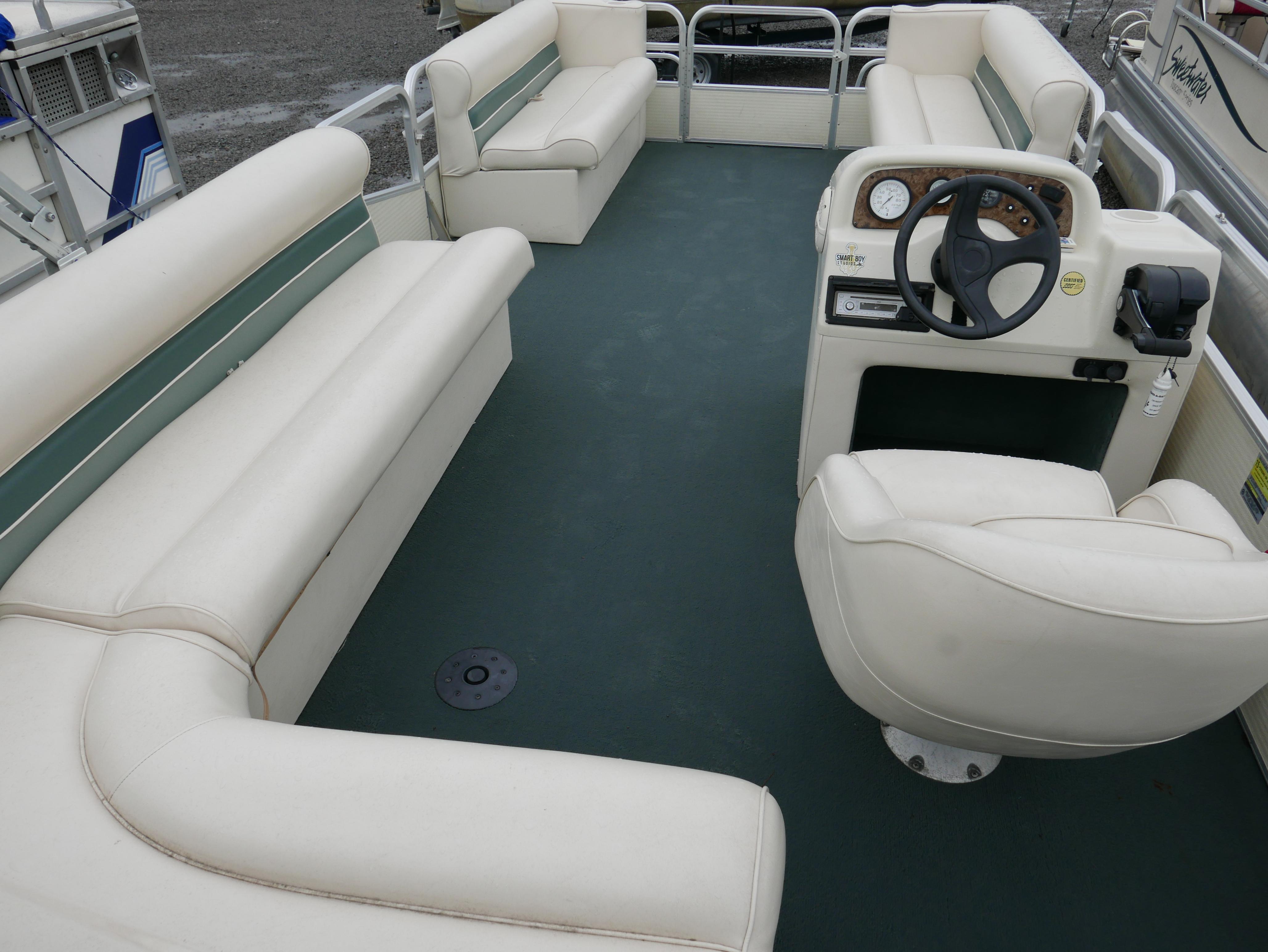 Slide: The Image of 2000 Riviera Cruiser pontoon boat interior with white seating and steering console. - 11