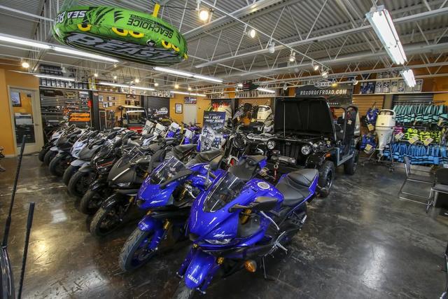 Slide: The Image of Showroom with motorcycles, off-road vehicles, and 2024 Robalo 206 Cayman boat. - 43