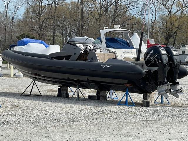 Slide: The Image of 2022 Roughneck RIB 1010 boat on stands, parked in a marina with other boats. - 25