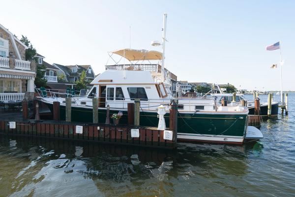 Slide: The Image of 2000 Sabreline 47 Motor Yacht docked at a marina with waterfront homes. - 0