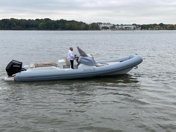 Slide: The Image of 2024 SACS Strider 900 boat cruising on a calm lake with a person at the helm. - 2