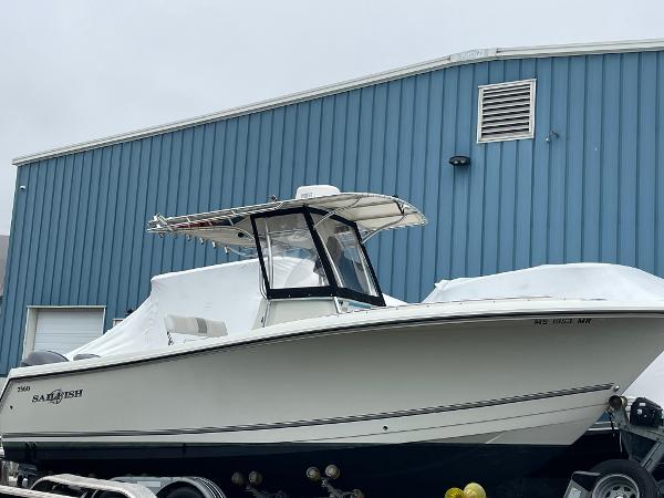 Slide: The Image of 2006 Sailfish 2360 CC boat on trailer near blue building. - 0