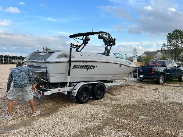 Slide: The Image of 2023 Sanger 231 SL boat on trailer, parked near a truck. - 16