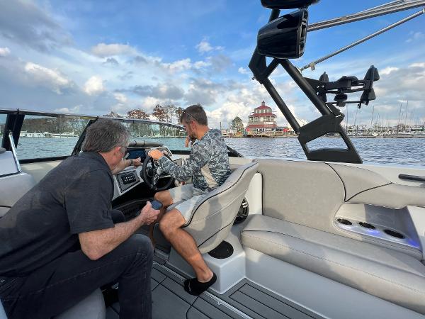 Slide: The Image of Two men on a 2023 Sanger 231 SL boat, navigating a scenic waterway. - 19