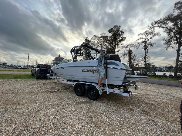 Slide: The Image of 2023 Sanger 231 SL boat on trailer at marina with cloudy sky. - 2