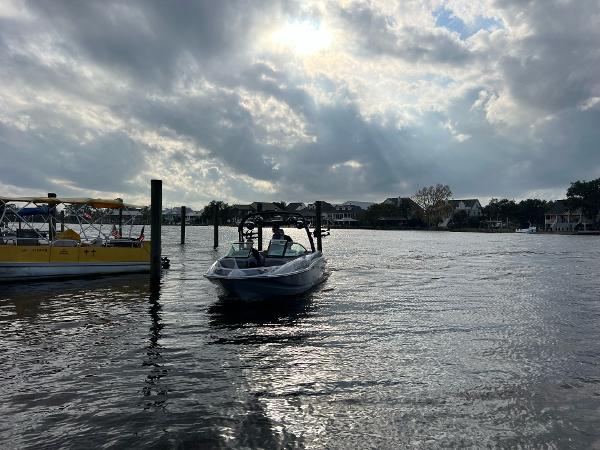 Slide: The Image of 2023 Sanger 231 SL boat on a cloudy lake with houses in the background. - 24
