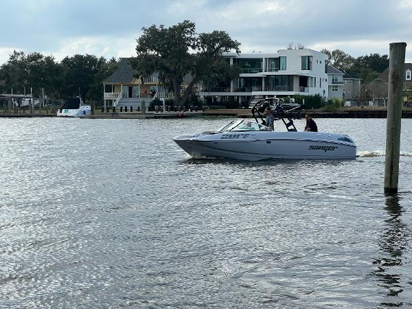 Slide: The Image of Sanger 231 SL boat cruising on a lake with modern houses in the background, 2023 model. - 26