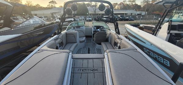 Slide: The Image of 2023 Sanger 231 SL boat interior with seating and dashboard, docked among other boats. - 40