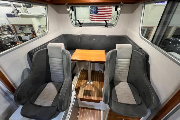 Slide: The Image of Interior of 2021 Sargo 25 boat with seating and table, American flag in background. - 23