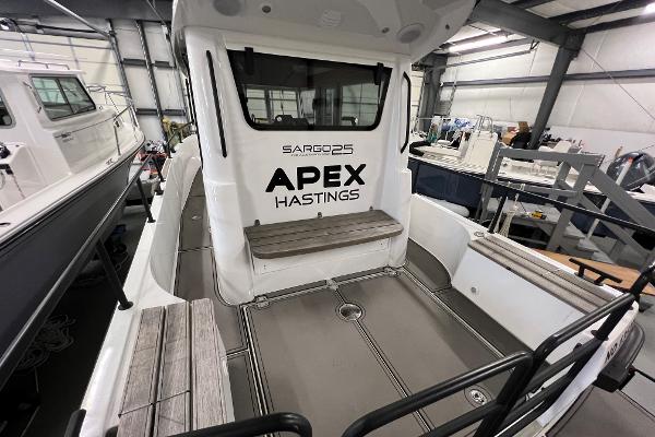 Slide: The Image of 2021 Sargo 25 boat interior with seating, labeled APEX HASTINGS, in a storage facility. - 37