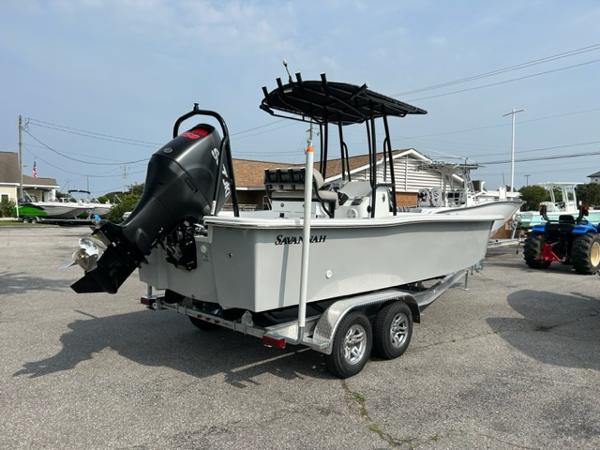 Slide: The Image of 2024 Savannah SS21 boat on trailer with outboard motor in a parking lot. - 2