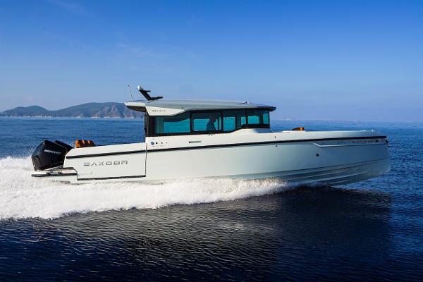 Slide: The Image of 2024 Saxdor 320 GTC cruising on open water with scenic mountain backdrop. - 1