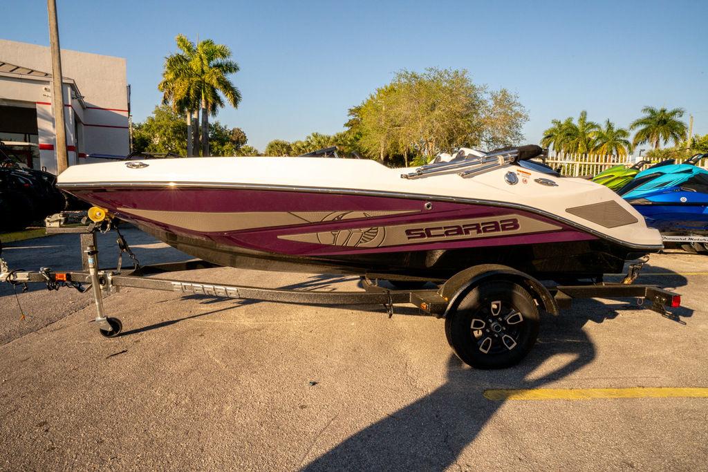 Slide: The Image of 2023 Scarab 165 ID boat on a trailer, parked outdoors near palm trees. - 0