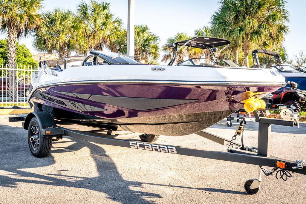 Slide: The Image of 2023 Scarab 165 ID boat on trailer with palm trees in the background. - 2