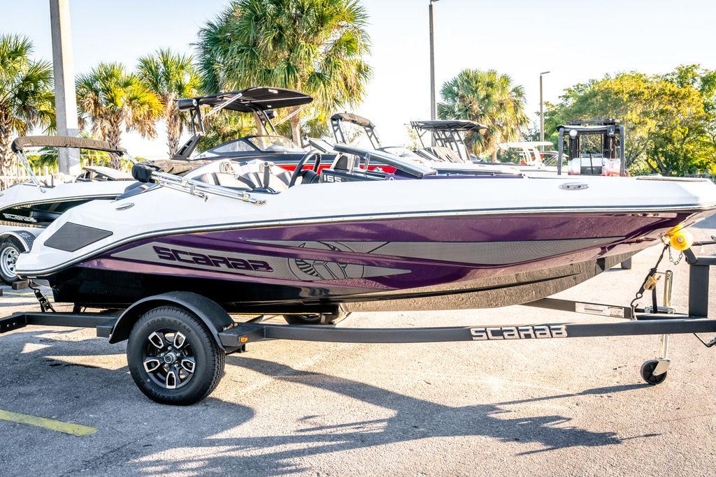 Slide: The Image of 2023 Scarab 165 ID boat on trailer, parked with palm trees in the background. - 3