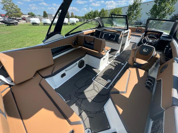 Slide: The Image of 2024 Scarab 285 ID boat interior with brown and white seating, open cockpit, and modern dashboard. - 14