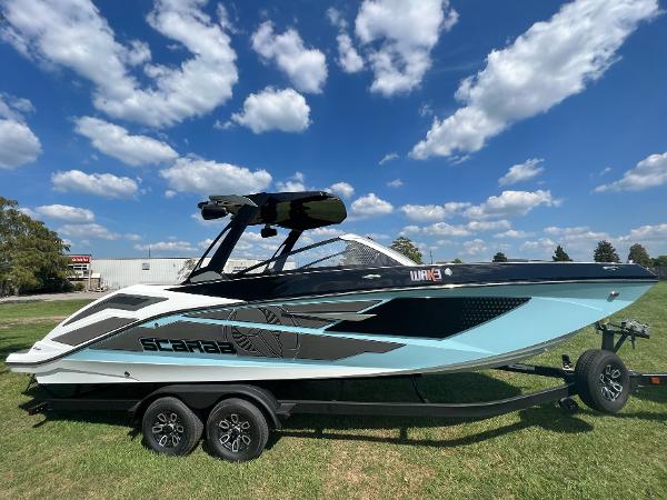 Slide: The Image of 2024 Scarab 285 ID boat on a trailer under a blue sky with clouds. - 3
