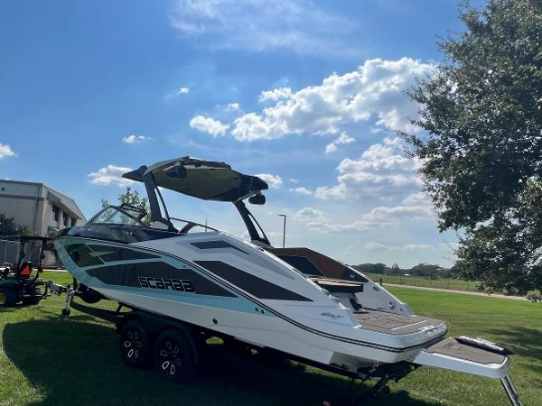Slide: The Image of 2024 Scarab 285 ID boat on trailer, parked on grass under blue sky. - 34