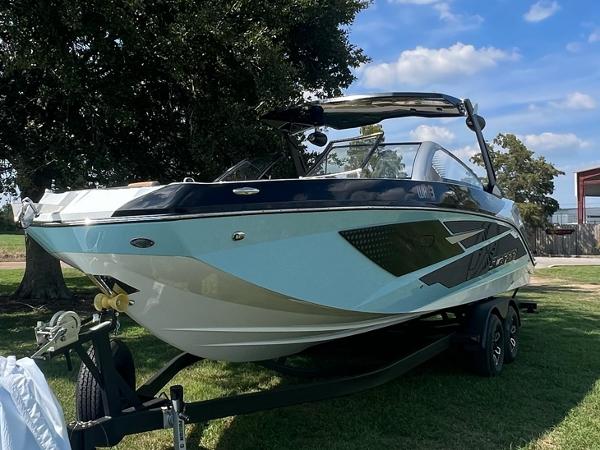 Slide: The Image of 2024 Scarab 285 ID boat on a trailer, parked on grass under a clear blue sky. - 5