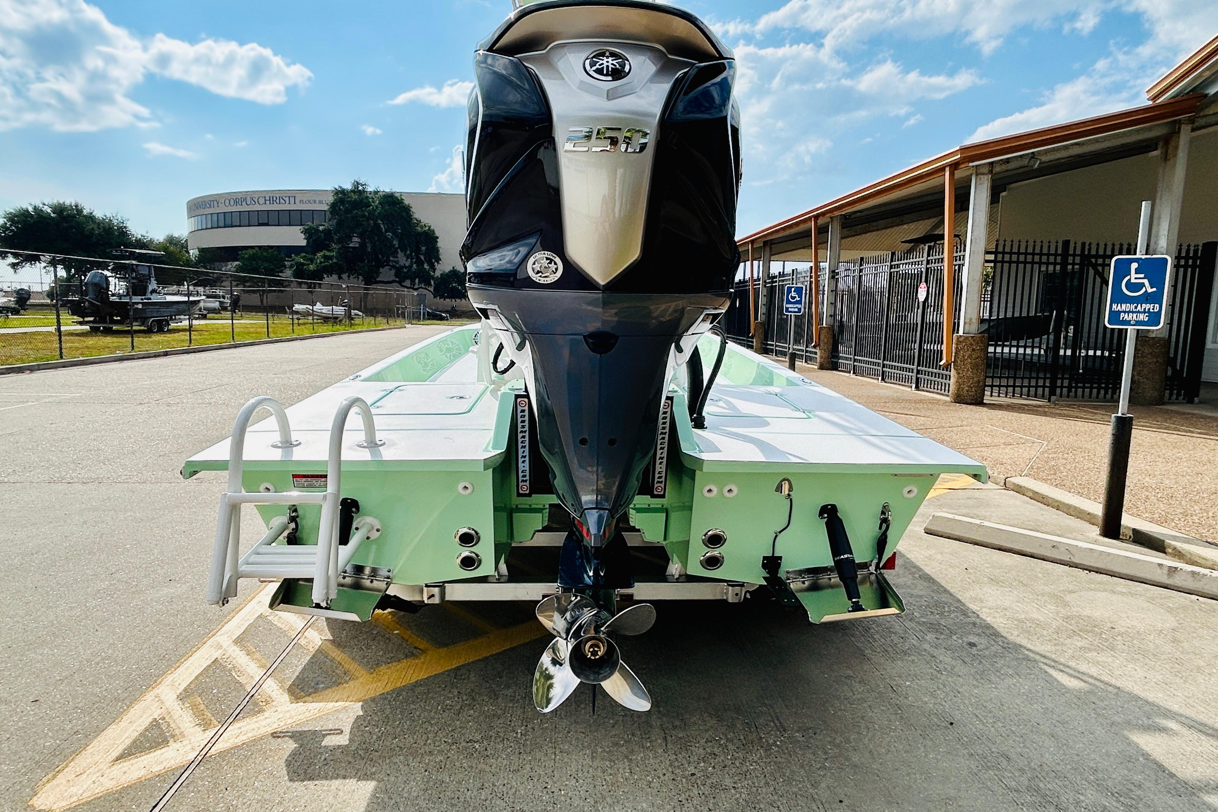 Slide: The Image of 2026 SCB R24 boat with powerful outboard motor, parked near a building under a clear sky. - 5
