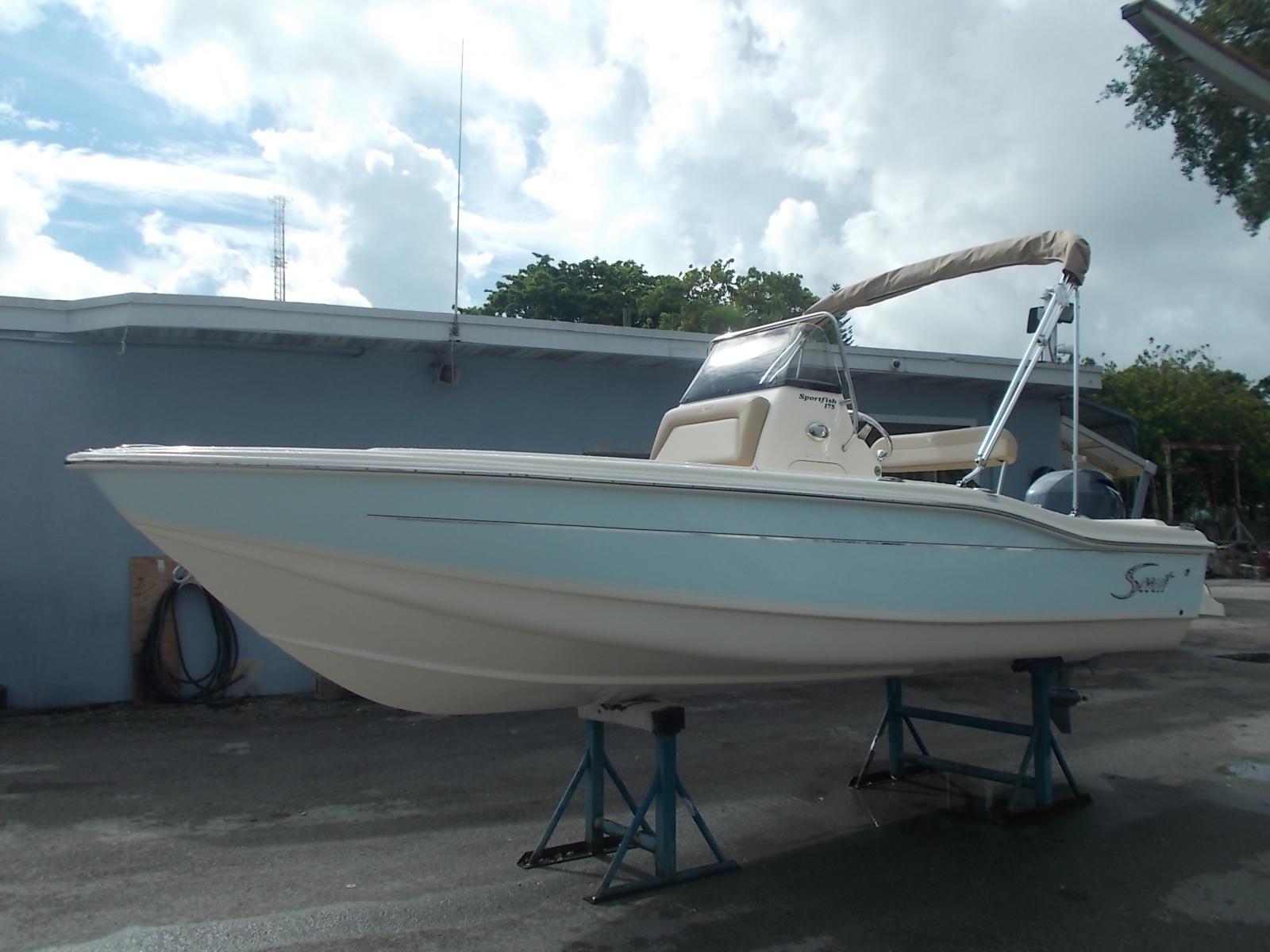 Slide: The Image of 2025 Scout 175 Sportfish boat on stands, light blue hull, parked outdoors. - 10
