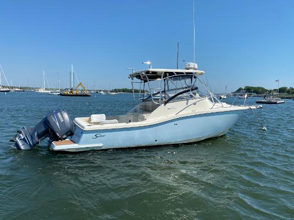 Slide: The Image of 2004 Scout 280 Abaco boat on water, clear sky, marina background. - 2