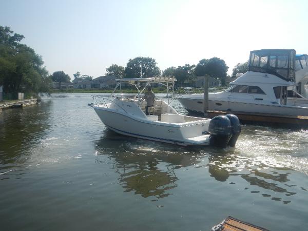 Slide: The Image of 2001 Scout 282 Abaco boat navigating a calm waterway near docked vessels. - 8