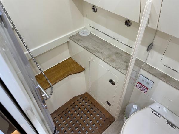 Slide: The Image of 2020 Scout 420 LXF boat bathroom with shower, wooden seat, and modern fixtures. - 23