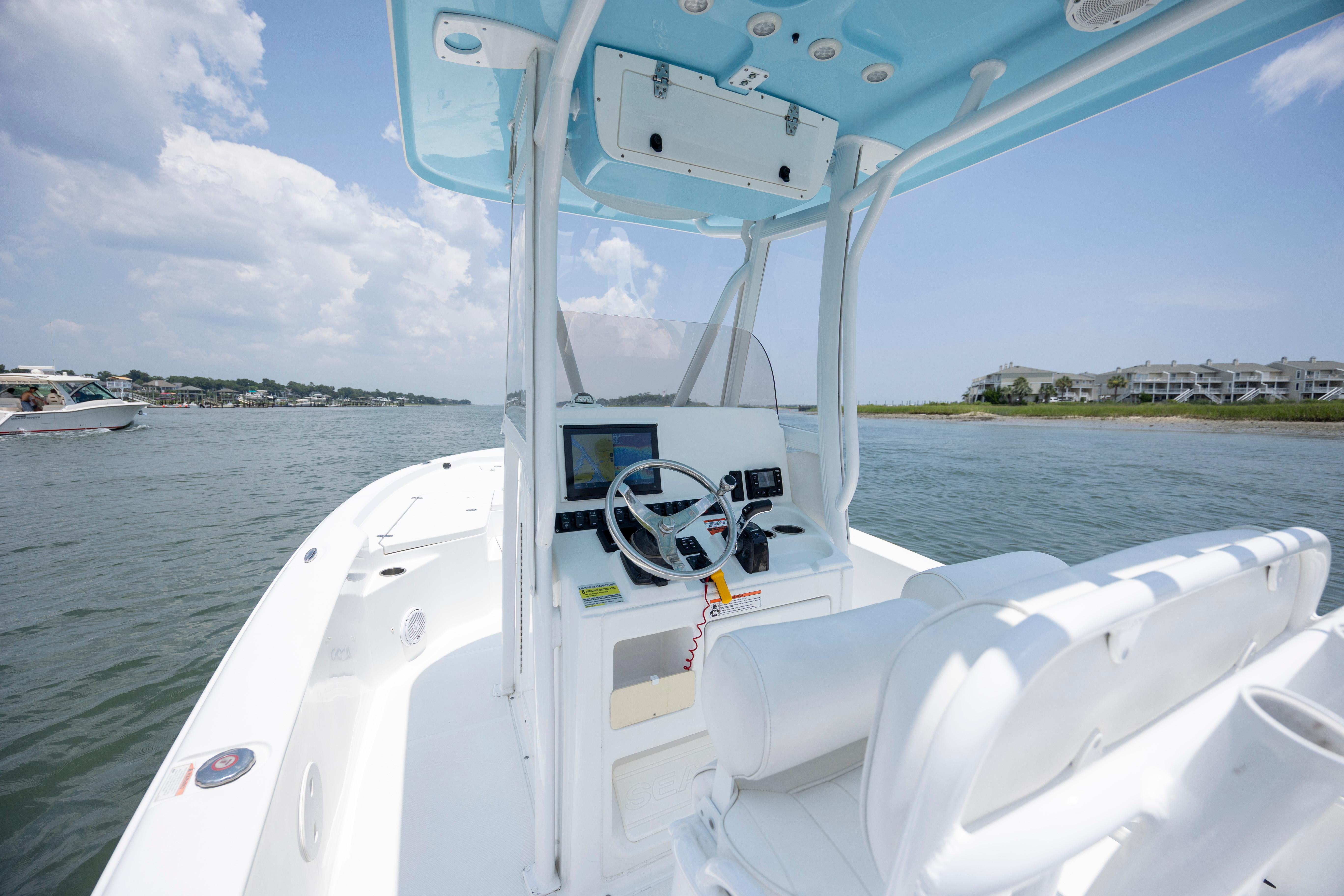 Slide: The Image of 2016 Sea Hunt BX 24 BR boat interior with steering wheel, on calm water, under blue sky. - 17