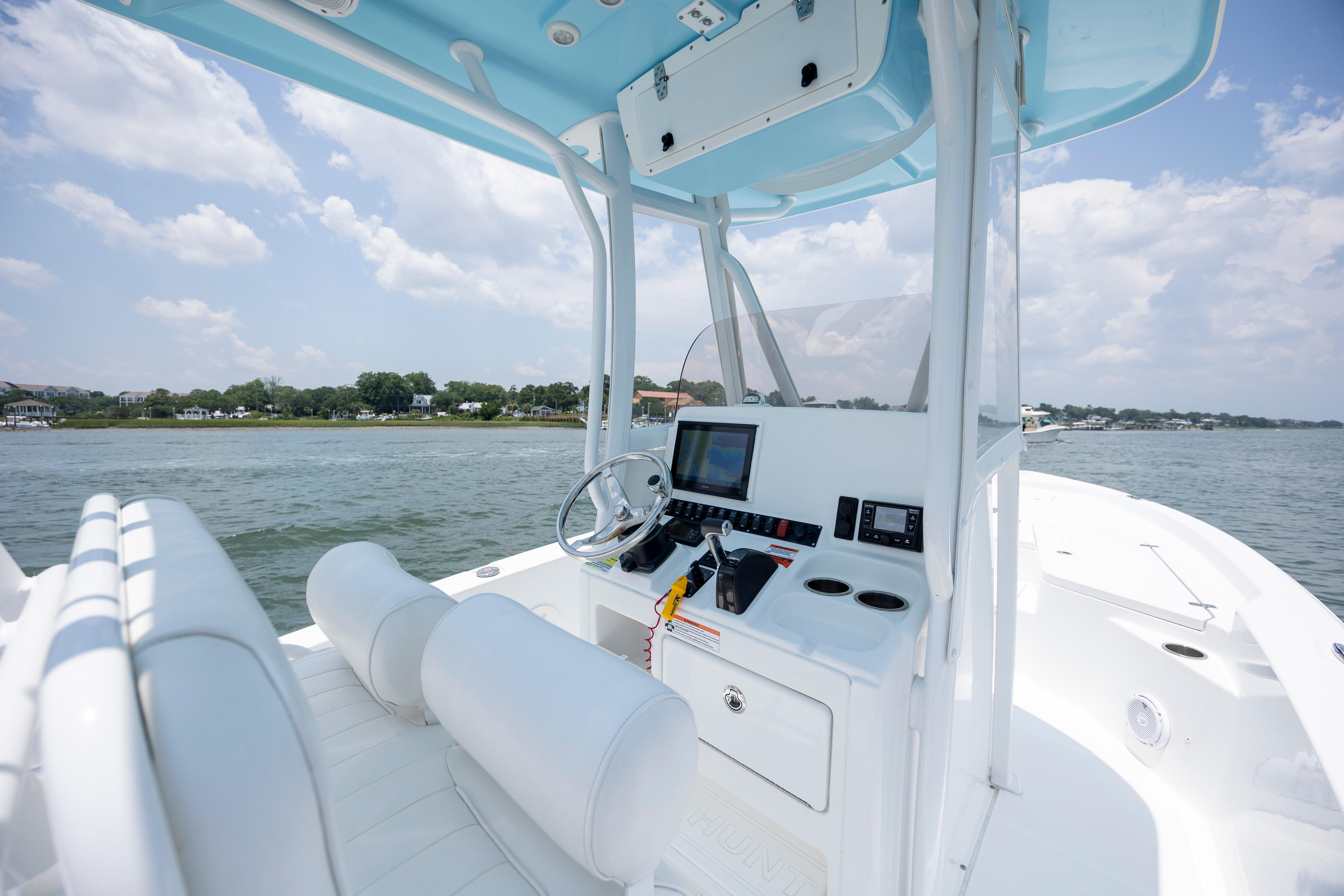 Slide: The Image of 2016 Sea Hunt BX 24 BR boat interior with steering console, on a calm waterway. - 19