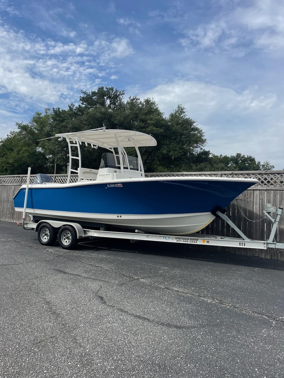 Slide: The Image of 2013 Sea Hunt Edge 24 boat on trailer, blue hull, parked outdoors. - 0