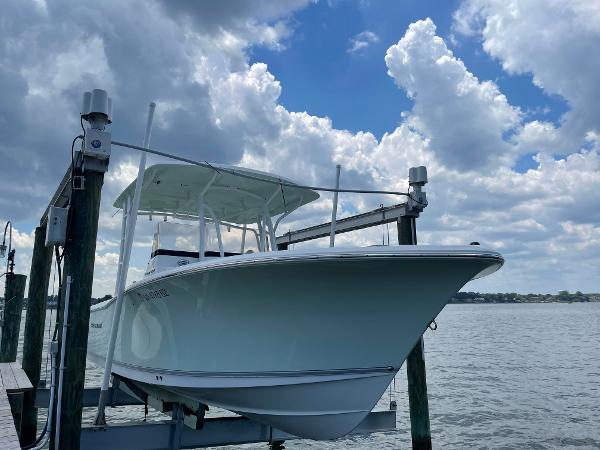Slide: The Image of 2015 Sea Hunt Edge 24 boat docked on a lift under a cloudy sky. - 0