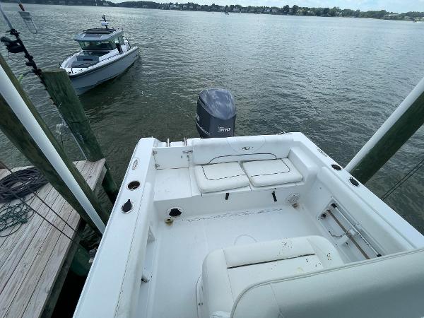 Slide: The Image of 2015 Sea Hunt Edge 24 boat docked, showing spacious deck and outboard motor. - 19