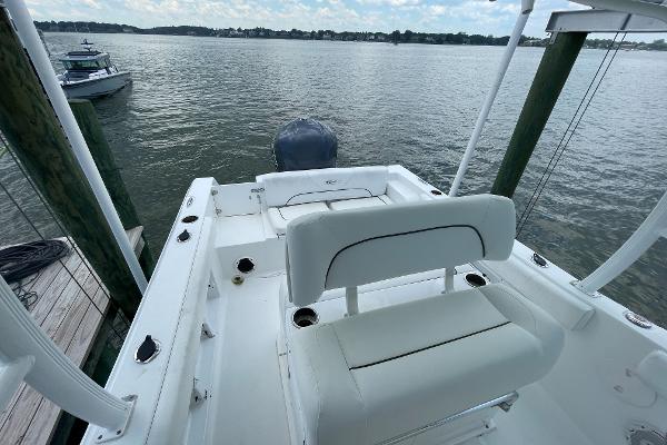 Slide: The Image of 2015 Sea Hunt Edge 24 boat docked by the water, featuring white seating and a rear motor. - 4