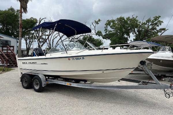 Slide: The Image of 2000 Sea Hunt Escape 200 boat on trailer, parked outdoors under cloudy sky. - 0
