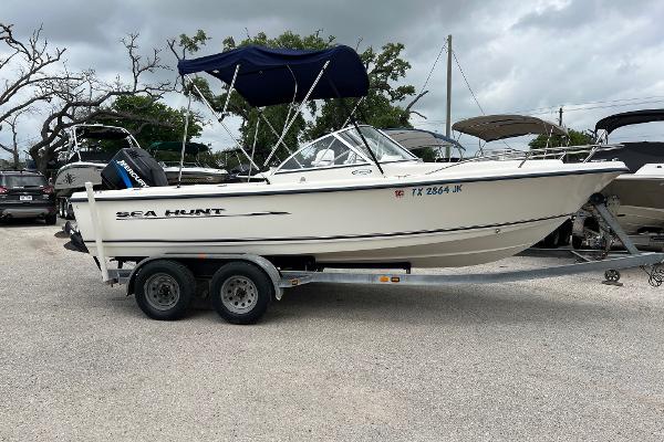 Slide: The Image of 2000 Sea Hunt Escape 200 boat on trailer, parked outdoors, with blue canopy. - 1
