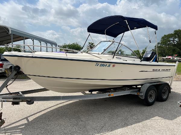 Slide: The Image of 2000 Sea Hunt Escape 200 boat on trailer with blue canopy, parked outdoors. - 24