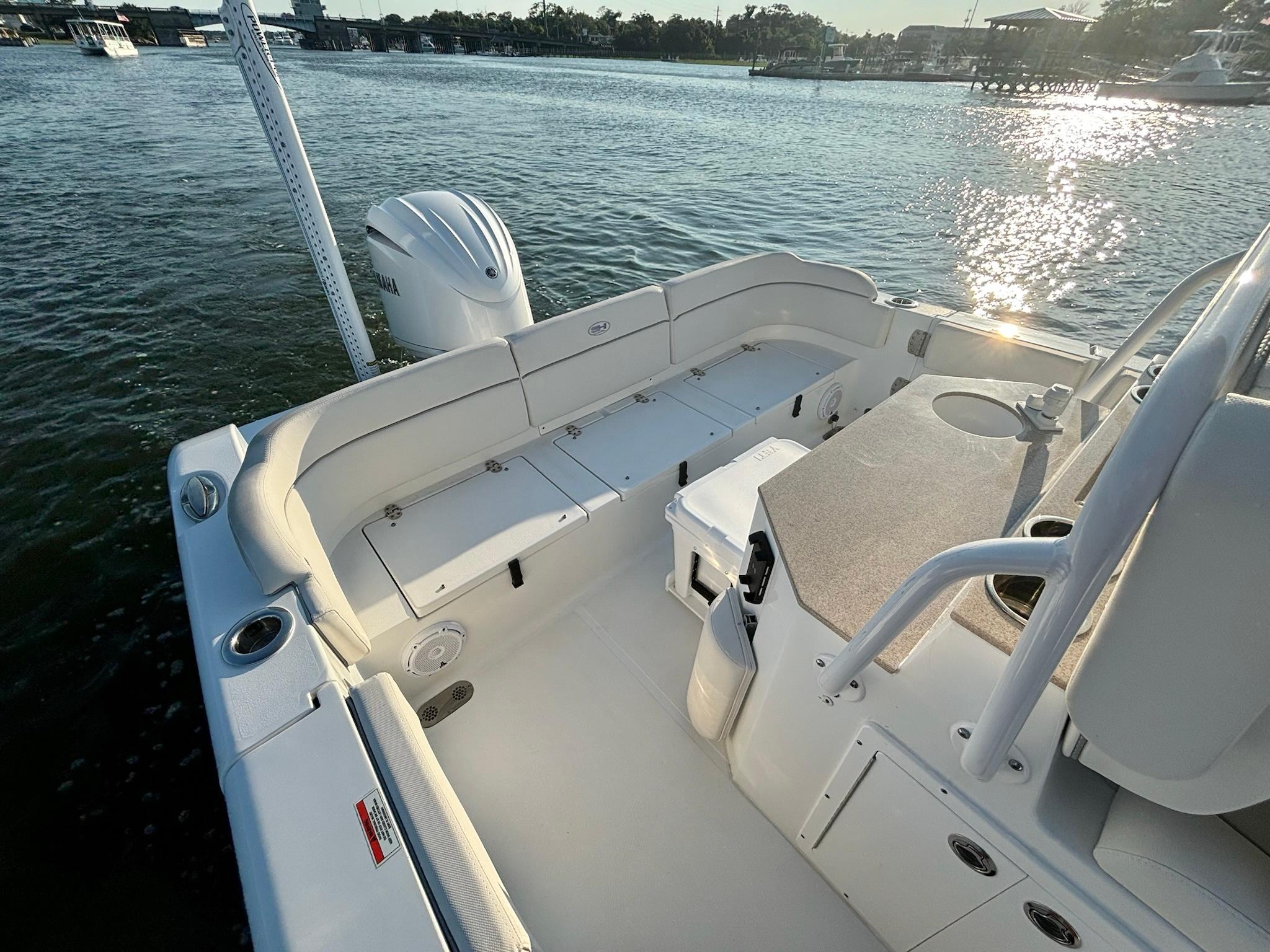 Slide: The Image of 2023 Sea Hunt Escape 25 boat interior with seating and storage, docked on a sunny day. - 11