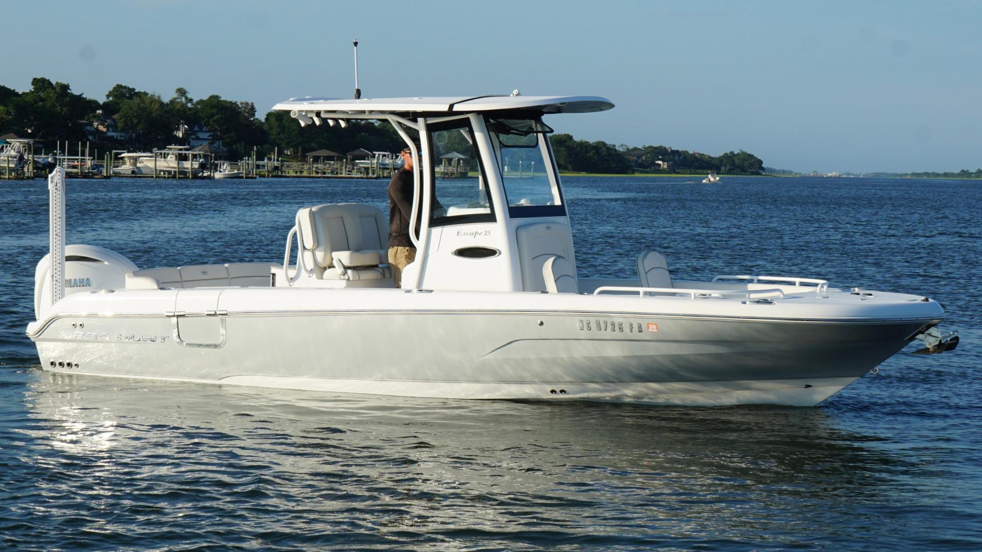 Slide: The Image of 2023 Sea Hunt Escape 25 boat cruising on a calm lake with scenic background. - 8