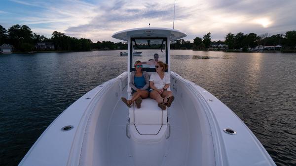 Slide: The Image of 2025 Sea Hunt Gamefish 27 Coffin Box boat on serene lake with passengers. - 24