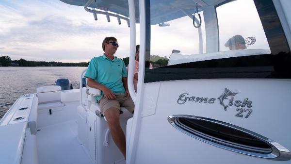 Slide: The Image of 2025 Sea Hunt Gamefish 27 Coffin Box boat on water, man seated, clear sky. - 27